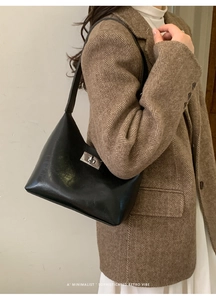 Detail of a minimalist black leather underarm bag with a vintage silver twist lock