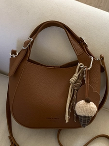 Brown lychee leather bucket crossbody bag with stylish woven charm and adjustable strap