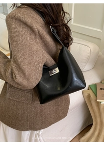 Detail shot of a black polished leather shoulder bag with a silver rectangular twist lock