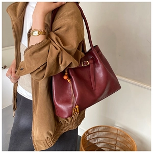 Vue détaillée du sac cabas en cuir bordeaux avec franges en bois et boucle dorée