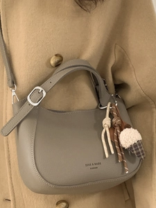 Taupe pebbled leather bucket bag with plush charm and adjustable shoulder strap