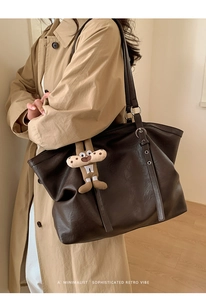 Macro detail of dark brown leather tote bag strap with silver buckle and gingerbread charm