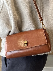Borsa a tracolla vintage in pelle marrone con fibbia dorata indossata da una modella