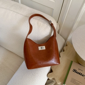 Retro brown leather shoulder bag with a silver rotary lock on a white fabric sofa
