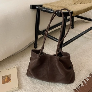 Close-up of a large dark brown leather tote bag with slim dual shoulder straps in a soft finish
