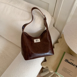 Detail of dark brown hobo bag with oil wax texture and silver metal twist lock