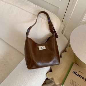 Detail of vintage brown shoulder bag with silver rectangle twist lock on white sofa