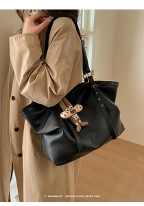 Detail of black faux leather tote bag with soft texture and adjustable metal buckle strap