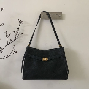 Close-up of black leather tote bag featuring gold rectangular buckle and minimalist design