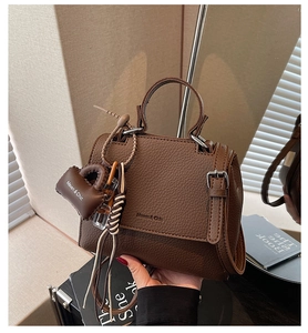 Close-up of brown litchi pattern leather handbag with Maven & Chic logo and top handle