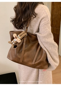 Close-up of retro brown leather tote bag with a cute plush dog pendant accessory