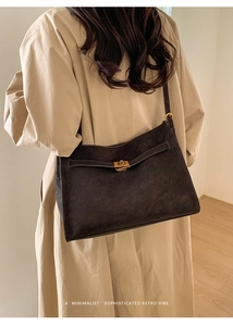 Detailed view of the dark brown suede bag with gold twist lock and adjustable shoulder strap