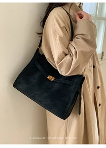 Detail of vintage black large tote bag with golden buckle on model's shoulder