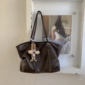 Close-up of vintage brown leather tote bag with silver rings and cute cartoon pendant
