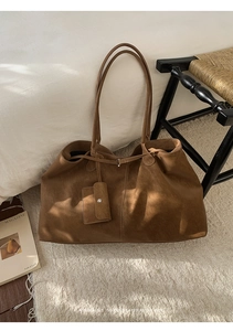 Détail de texture du grand cabas marron en daim avec sa mini pochette suspendue assortie