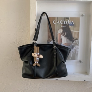 Detail of black faux leather tote bag with silver hardware and cute character charm