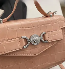 Détail d'un sac à main rose orangé à texture crocodile avec fermoir cœur en métal argenté