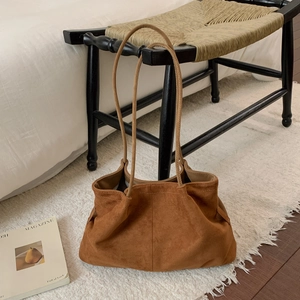 Detailed macro view of brown suede material and soft pleated texture on the tote bag