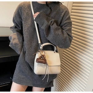 Detail of off-white lychee texture leather crossbody bag with logo and brown charm