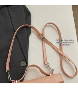 Détail du sac rose poudré effet croco montrant les boucles réglables de la bandoulière