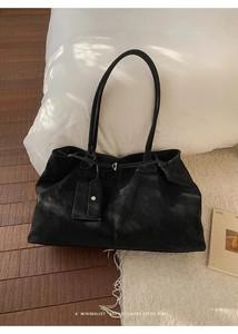 Détail d'un sac cabas noir minimaliste avec pochette assortie sur parquet rétro