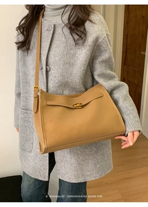 Detail view of the elegant golden twist lock and smooth camel leather texture on the tote bag