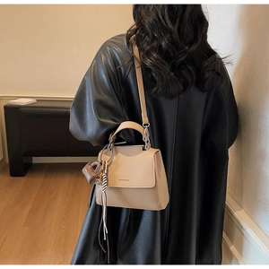 Detail of beige pebble leather handbag with heart charm and tassel for women