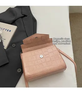 Gros plan sur la texture crocodile rose et le fermoir magnétique de ce sac à main