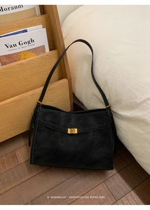 Detail shot of a black vintage minimalist tote bag with golden buckle in warm indoor light