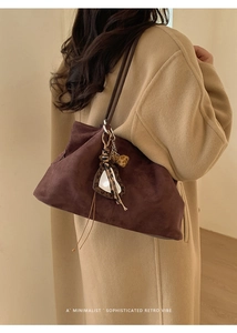 Detail of a retro dark brown suede tote bag with heart mirror charm and animal print strap