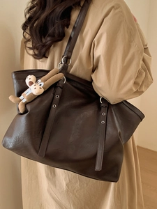 Grande borsa tote marrone retrò con ciondolo a cane indossata con un trench chic