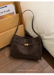 Detail showing high-quality lychee texture leather and gold metal buckle on dark brown bag