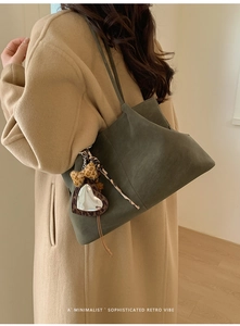 Detail of dark green suede tote bag with leopard heart charm on beige winter coat
