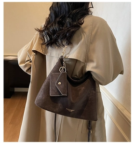 Gros plan du sac hobo marron foncé avec détails dorés sur un trench-coat beige