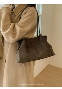 Close-up of minimalist retro dark grey suede tote bag shown on model in a camel coat