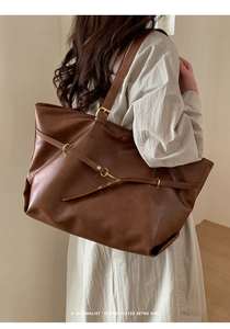 Macro shot of dark brown retro tote bag showing smooth leather texture and metal buckle