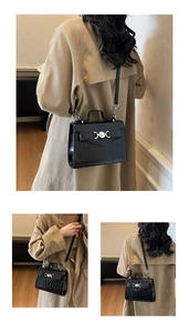 Dettaglio borsa nera stampa coccodrillo con fibbia a cuore d'argento su cappotto beige