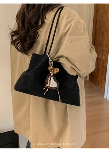 Minimalist black suede tote bag with leopard print heart charm shown on model's shoulder