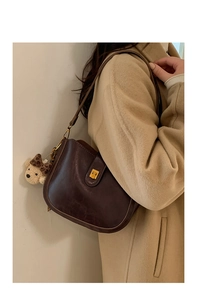 Detail of dark brown vintage shoulder bag with golden lock and leopard bow bear charm