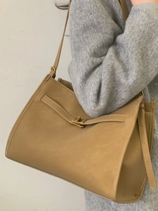 Khaki leather tote bag with metal flip-lock and adjustable strap shown on model