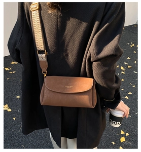 Détail d'un sac bandoulière en cuir marron mat avec une large sangle jacquard géométrique