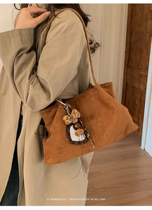 Detailed view of brown suede tote bag with leopard print mirror charm on model shoulder
