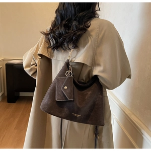 Détail d'un grand sac cabas en daim marron avec bandoulière et pochette suspendue