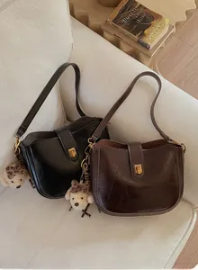 Close-up of black and coffee leather shoulder bags with cute leopard plush bear charms