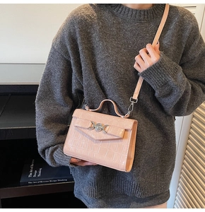 Détail de la texture crocodile rose sur le petit sac à main avec serrure en cœur