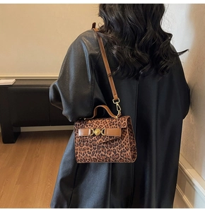 Dettaglio di una borsa leopardata con chiusura a cuore dorata e tracolla marrone scuro