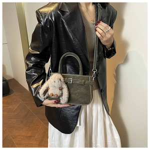 Detail of olive green vintage handbag with leather texture and cute rabbit charm