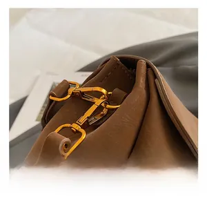 Gros plan du crochet doré et de la texture du cuir marron mat sur le sac à main