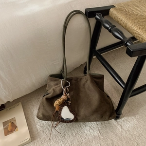 Detail view of olive green suede tote bag featuring heart mirror and leopard print charms