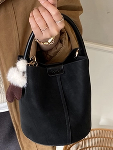 Elegante borsa a secchiello nera opaca da donna con ciondolo peluche e fibbia in metallo